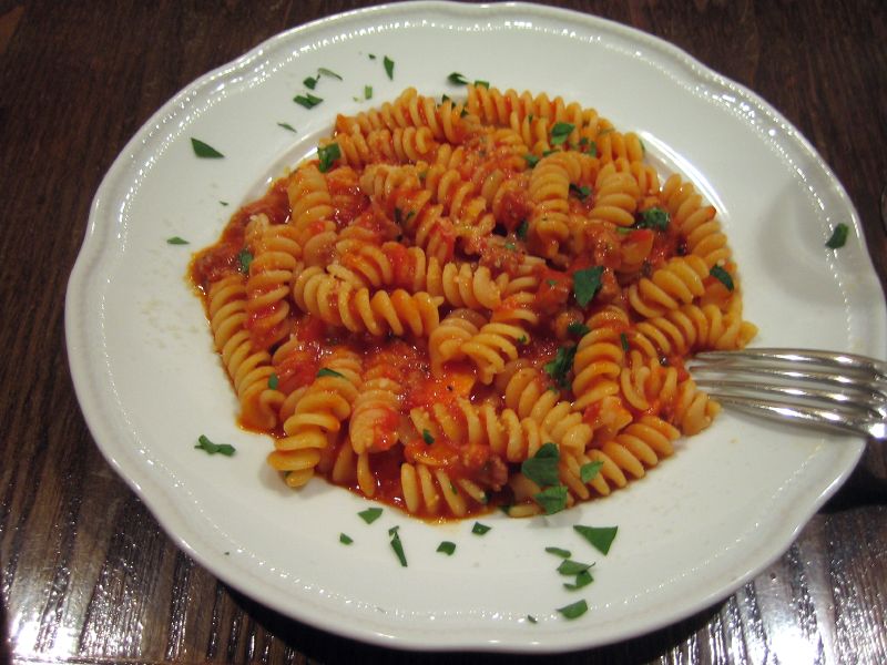 a pasta dish with sauce, greens and a fork
