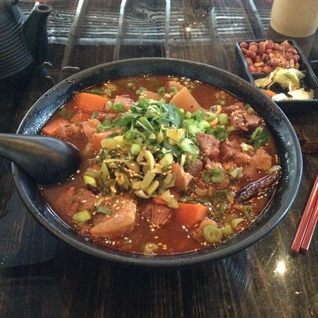 a bowl filled with soup, meats, veggies and asian rice