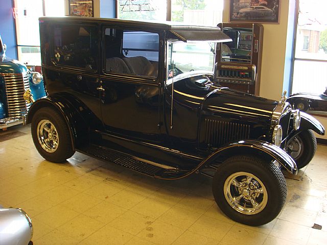 an antique model t car parked in front of two older cars