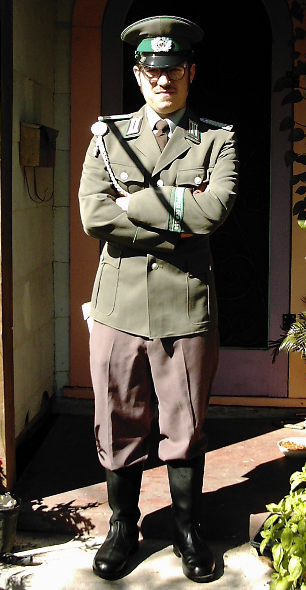 a man wearing an army uniform stands in front of a doorway