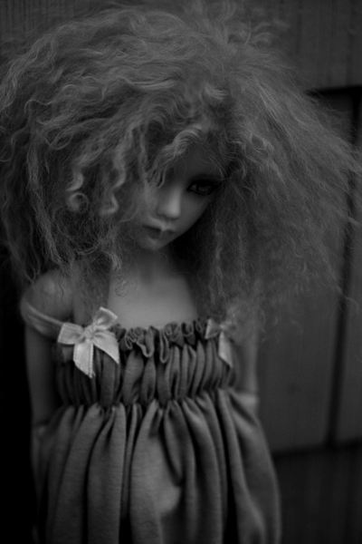 a doll with curly hair is wearing a brown dress
