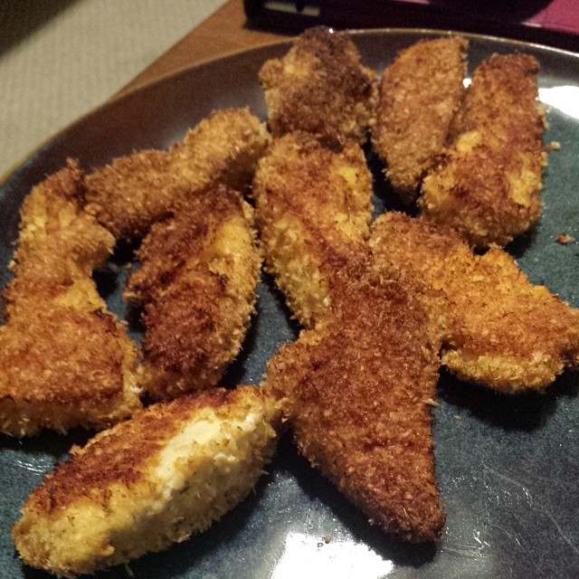 a plate filled with fried chicken strips on top of a wooden table