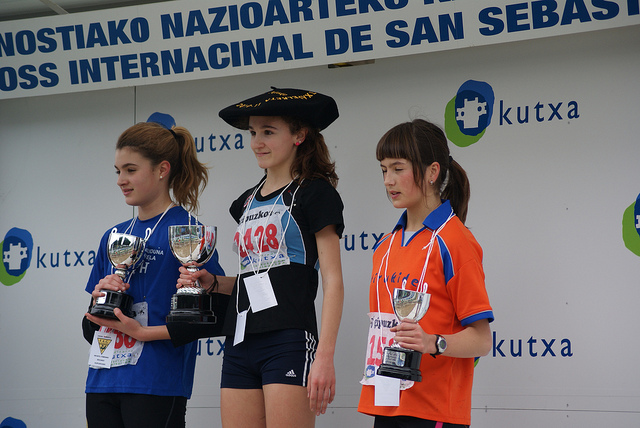 three s in running outfits hold up their trophies