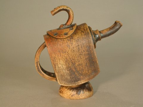 a wooden cup with a handle and some leaves on it