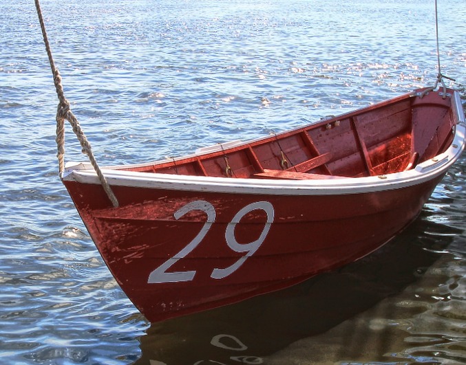 a red boat sits next to the water with number 29 on it