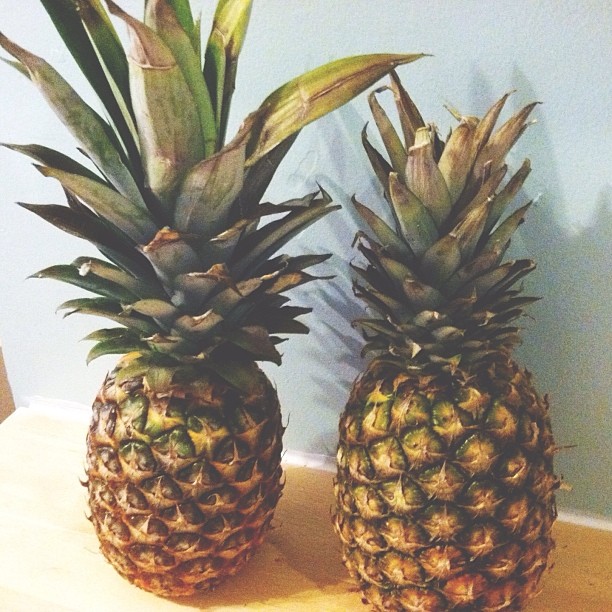 pineapples on a table with the leaves of a plant in between