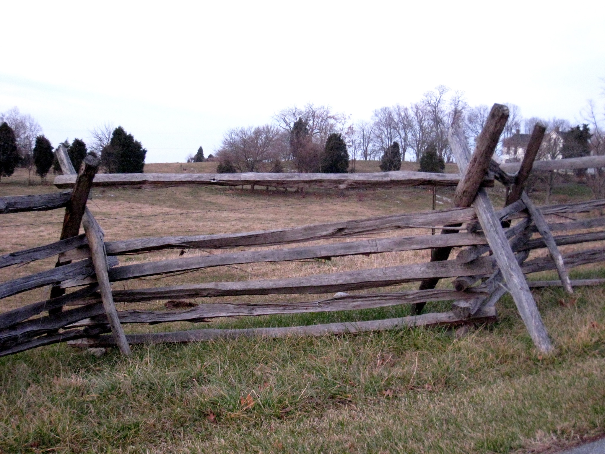 an old split rail fence is surrounded by grass