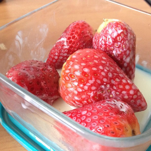 a plastic container containing strawberries in yogurt
