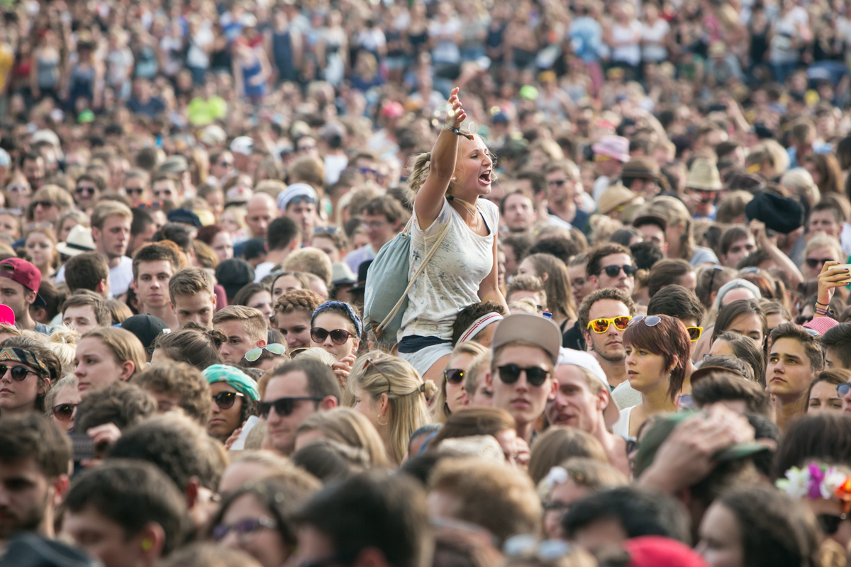 a woman holding her hand up to her face while she is in the middle of an audience