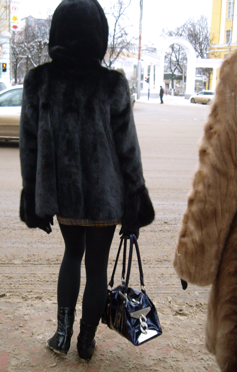 a woman in a very large fur coat walking down the street