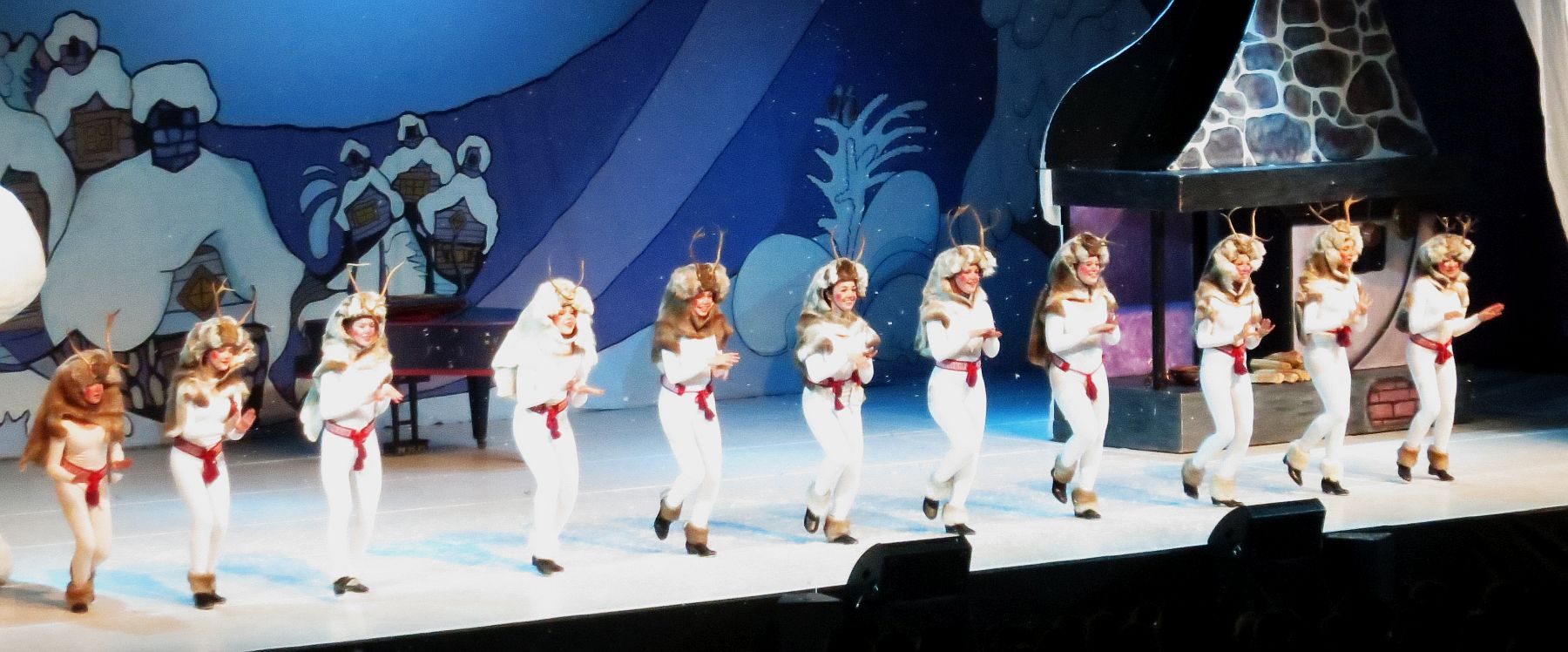 a group of dancers in white costumes perform on a stage