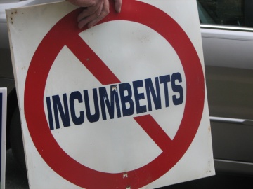 a hand holding a sign that says no incumbents on it