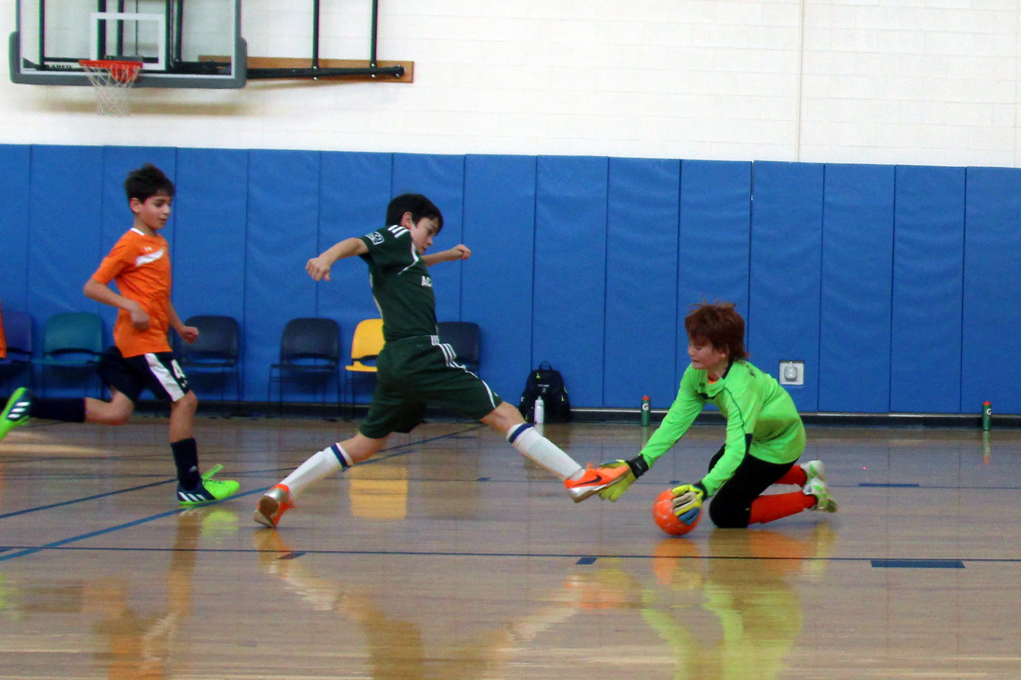 a group of young men kicking around an orange ball