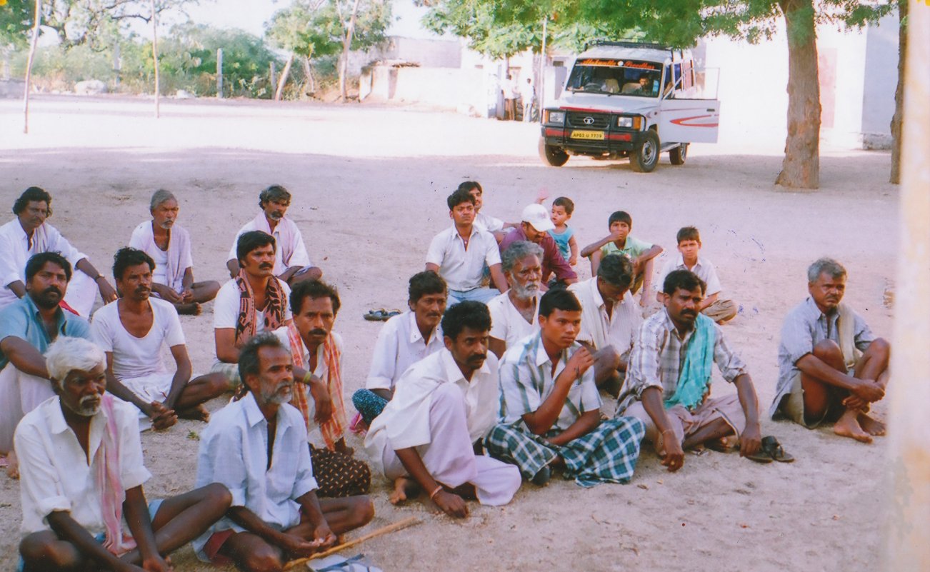 several men sitting on the ground next to each other