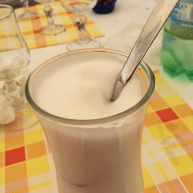 a glass with milk sitting on a table