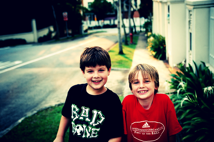 two s pose for a picture in front of a sidewalk