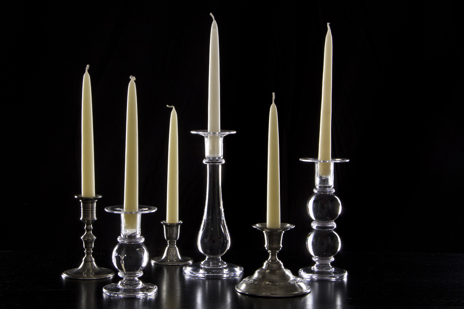 a group of tall glass candles with a small white candle in each