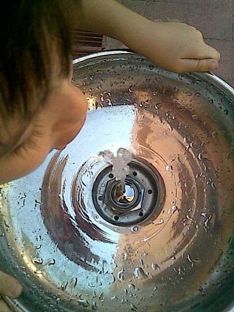 a young child in the middle of water coming from an inside sink