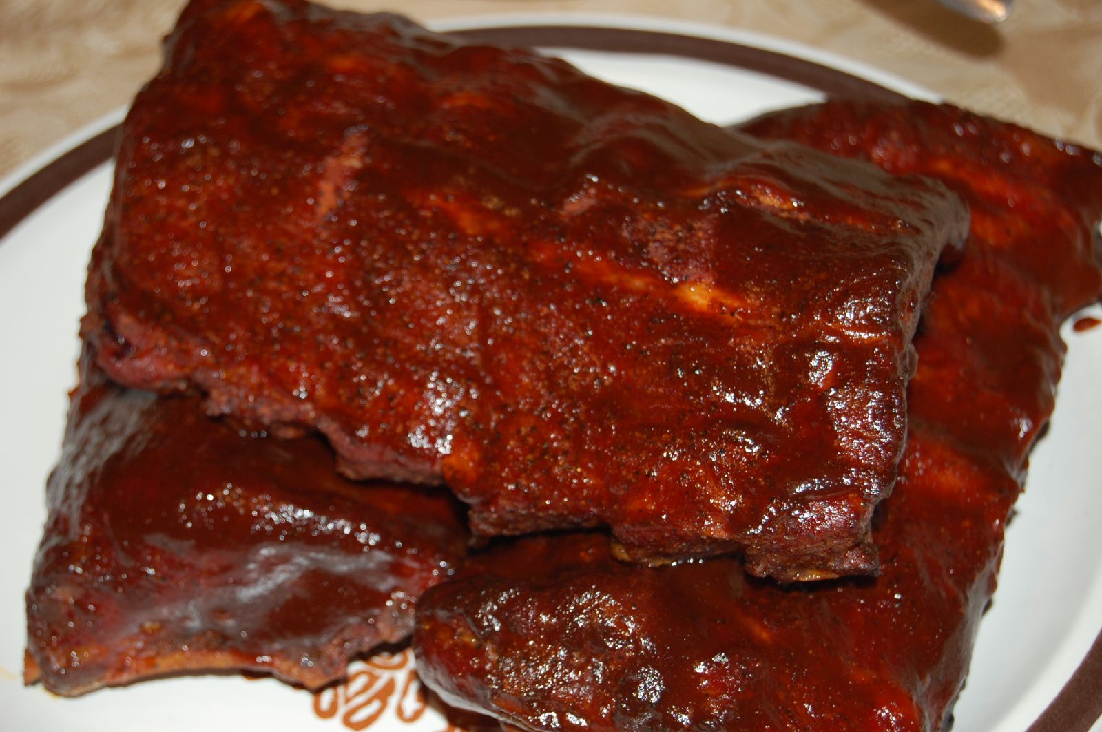 a plate with ribs covered in sauce and brown rim