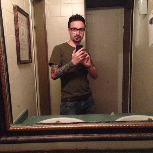 a man standing in front of a mirror while using a cell phone