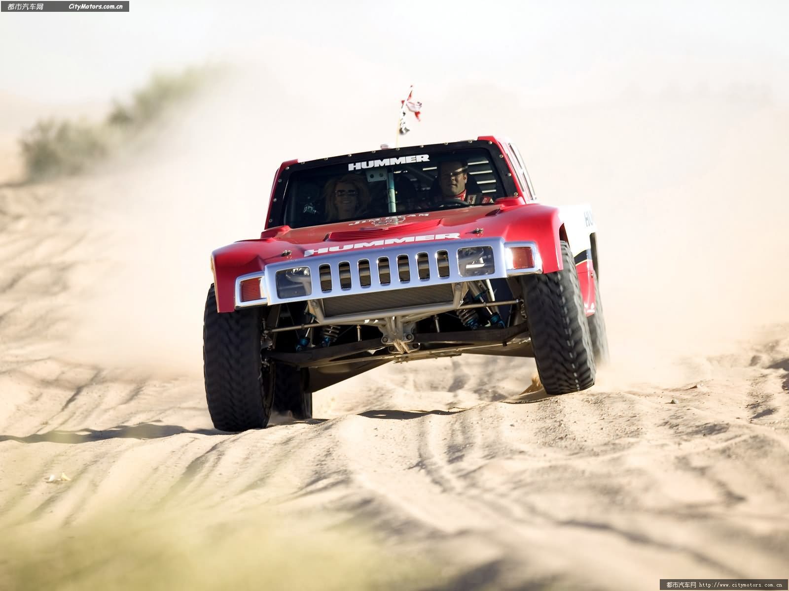 a truck driving through sand dunes on a sunny day