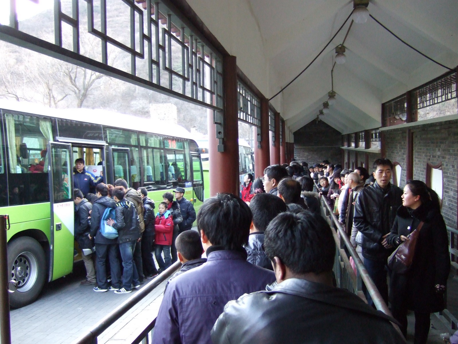 people crowding at a bus station waiting to board