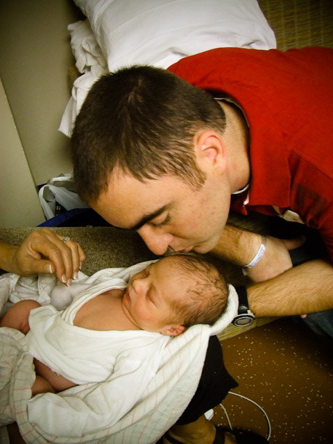 a man is kissing a newborn baby's cheek