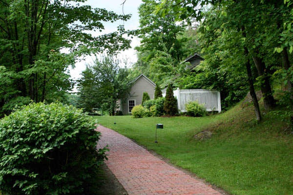 an overgrown brick path leading to a house
