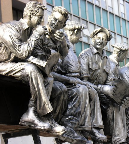 several statues sitting on top of a bench in front of a tall building