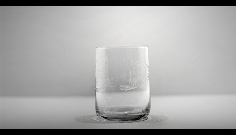 an empty glass sitting on a table in black and white