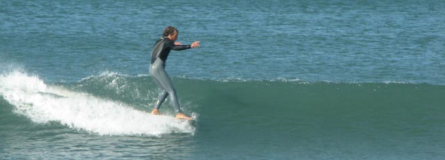 man in wetsuit surfing waves in open ocean