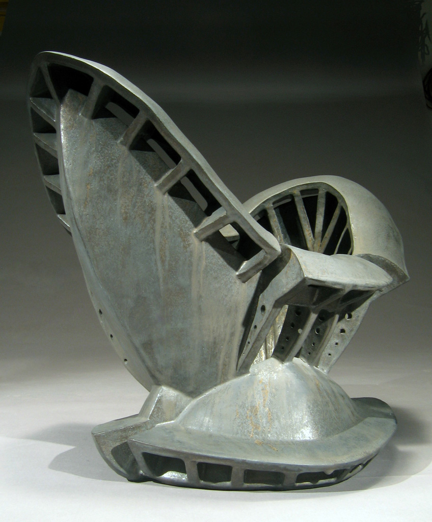 an iron sculpture sitting on top of a metal base