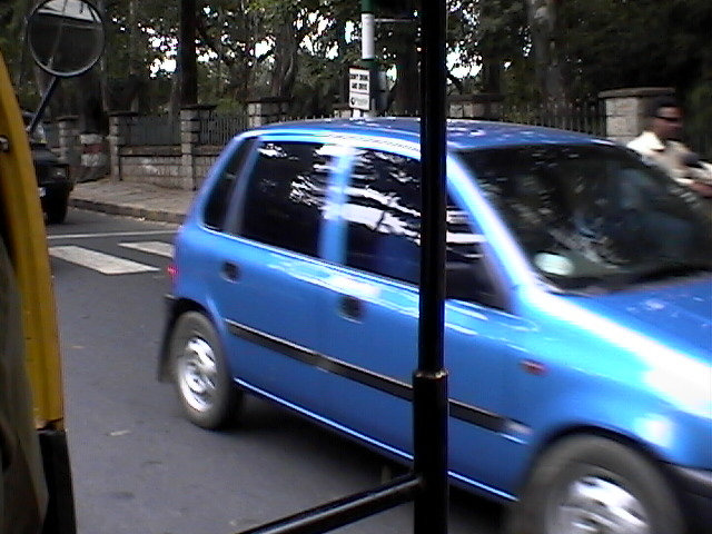 a blue car on the street near some parked cars