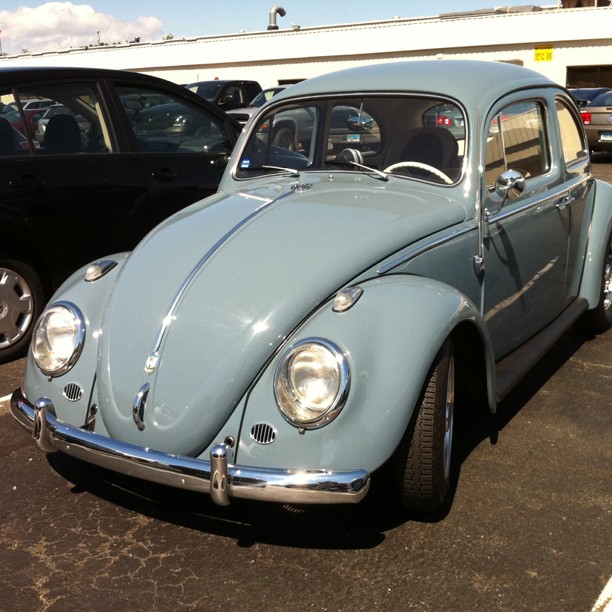 a bug sits parked on a parking lot next to several other cars