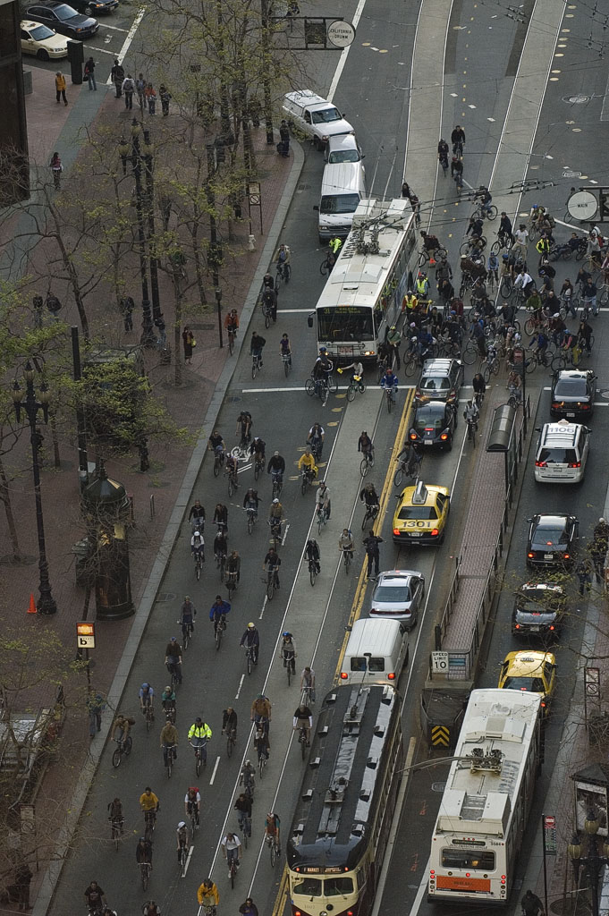 large amount of buses and motorcycle riders near a street