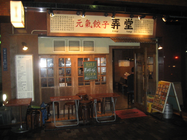 a restaurant with wooden table chairs sitting under a sign