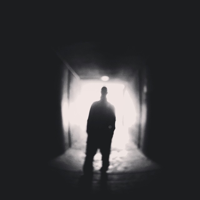 a man standing alone in an otherwise dark hallway