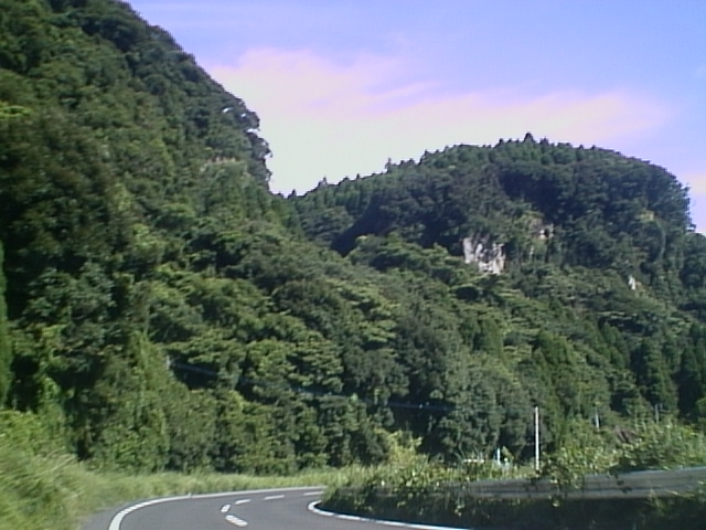 an open road surrounded by tall green mountains