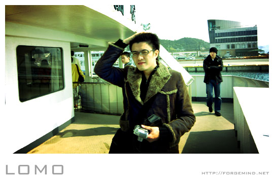 a man with glasses standing on a ferry next to other passengers