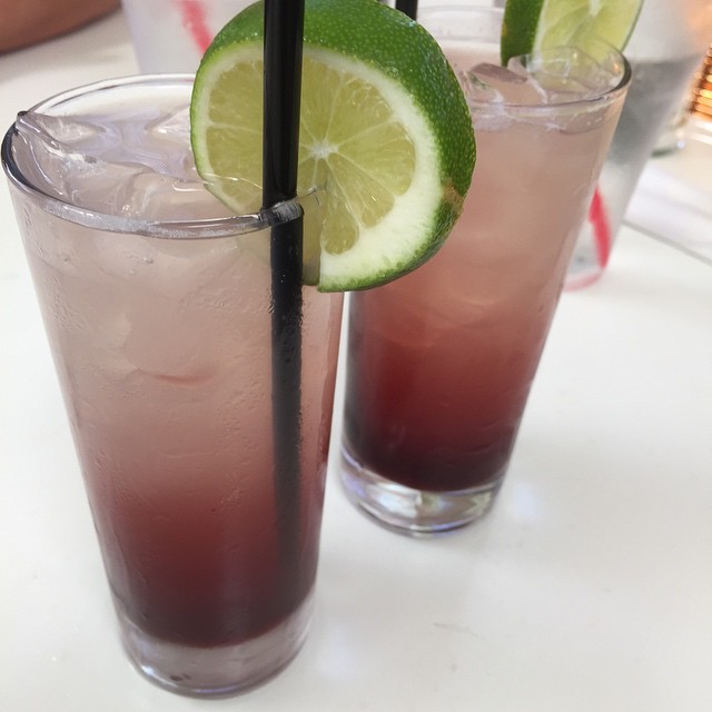 two drinks with straws and lime wedges on a table