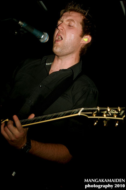 the man has his mouth open as he plays the guitar