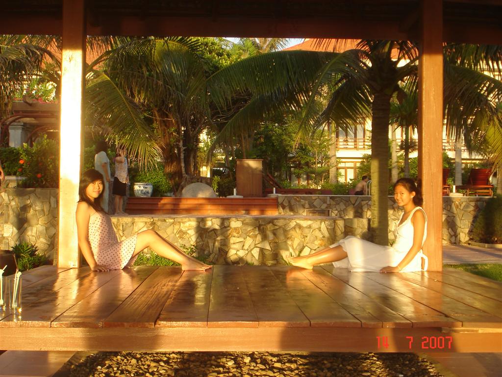 two women sitting on a wooden floor with plants