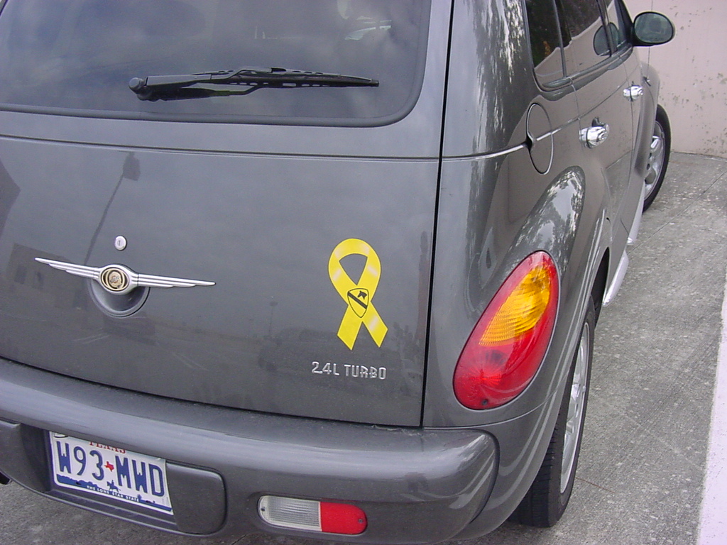 the back end of a grey car with a yellow ribbon