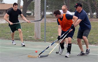three men playing hockey together in the court