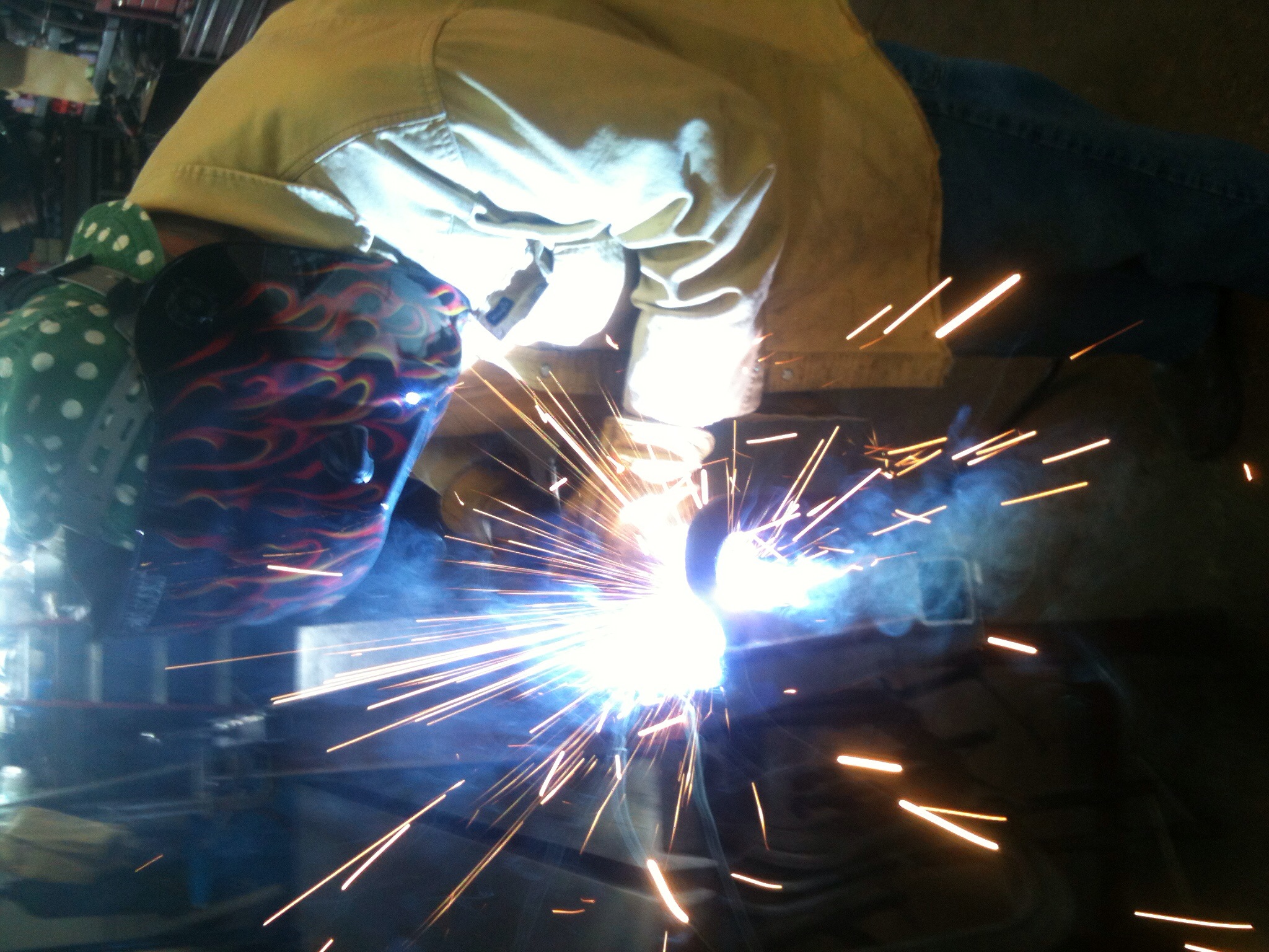 a woman wearing safety glasses holds a tool that's been welding into steel