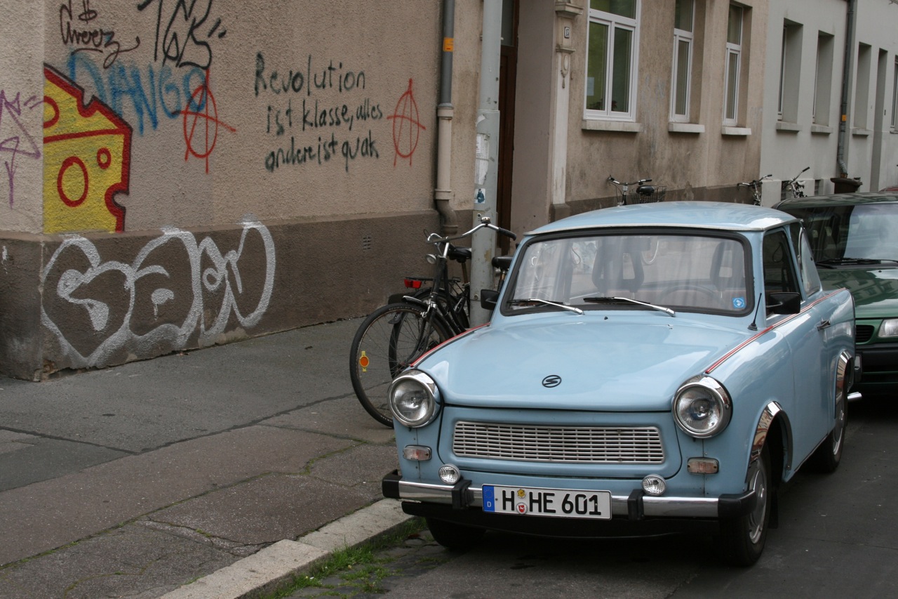 two old cars are parked on the side of a street