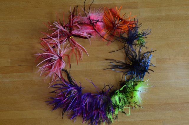 various dyed feathers arranged on a wooden surface
