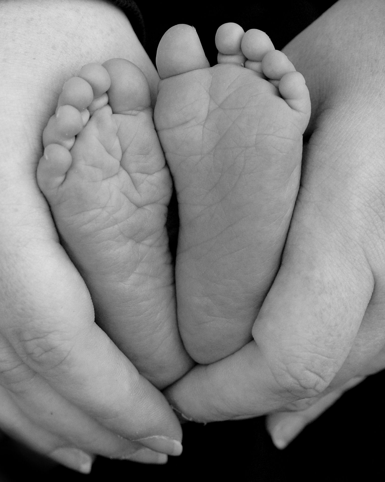 the hands of a woman holding a baby's feet