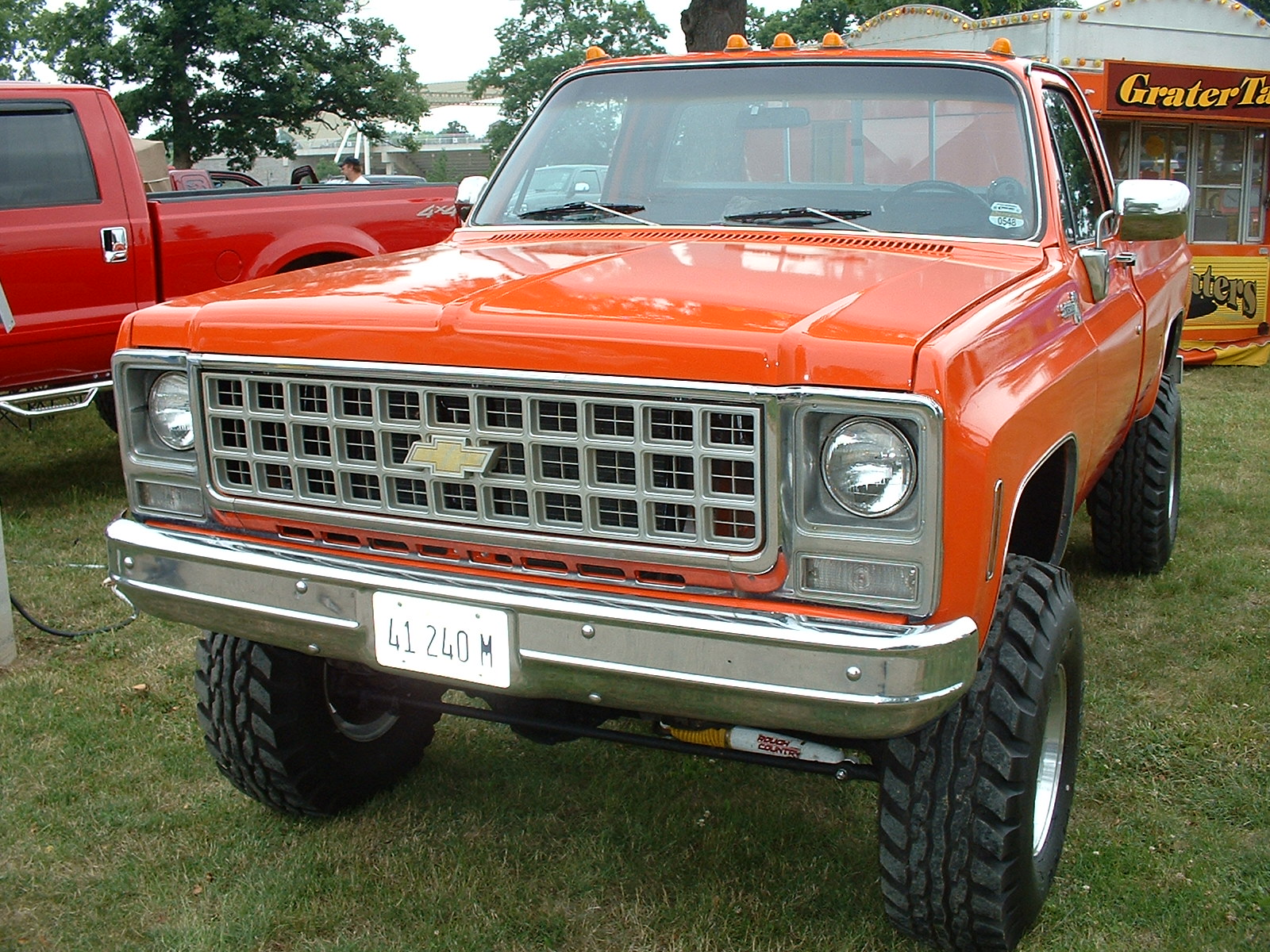this is an image of a orange truck parked at a car show