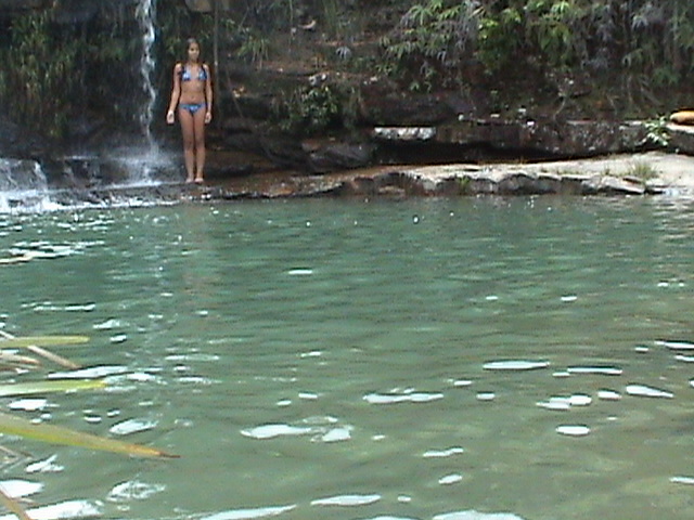 a girl in a bikini standing next to a waterfall
